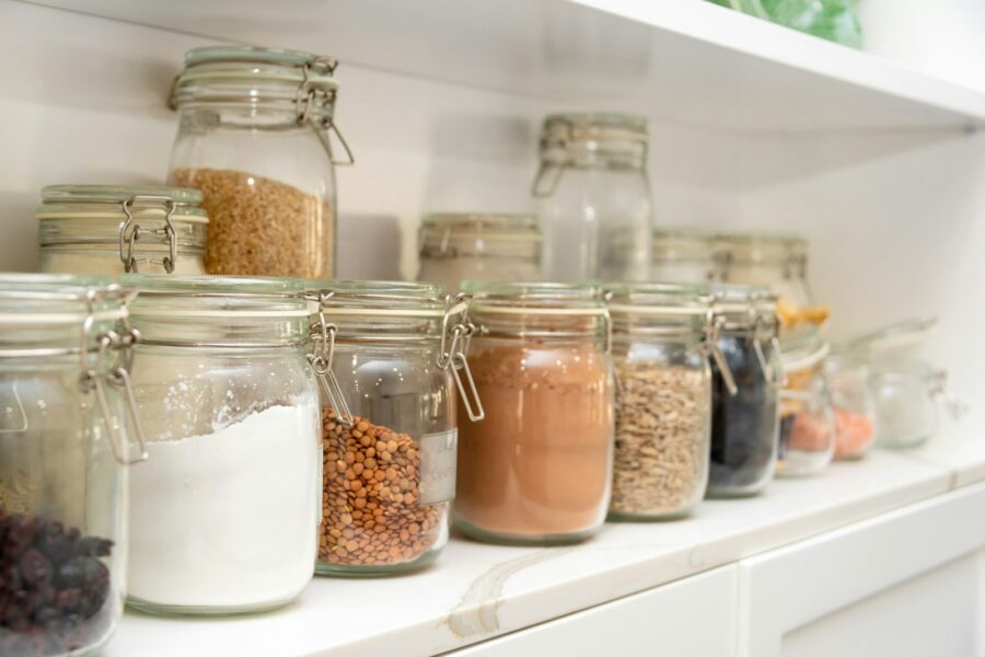 Glazen voorraadpotten met meel en muesli in een schone keukenkast