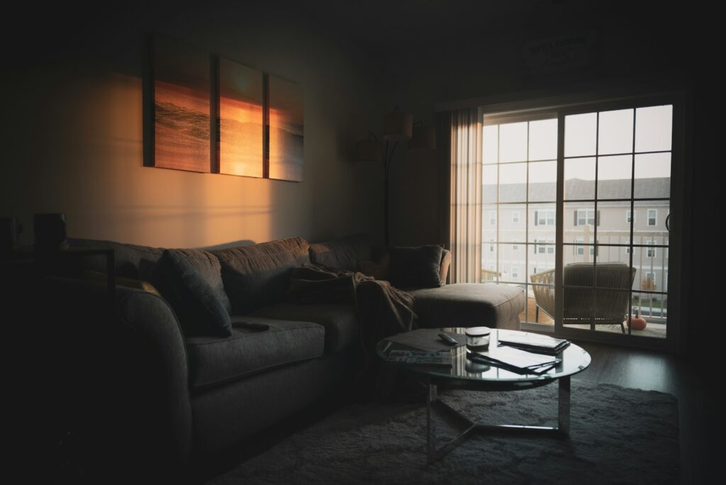 Stofdeeltjes in zonlicht boven een bank met kussens in een woonkamer
