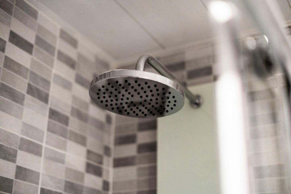 Een douchekop in een badkamer met tegels