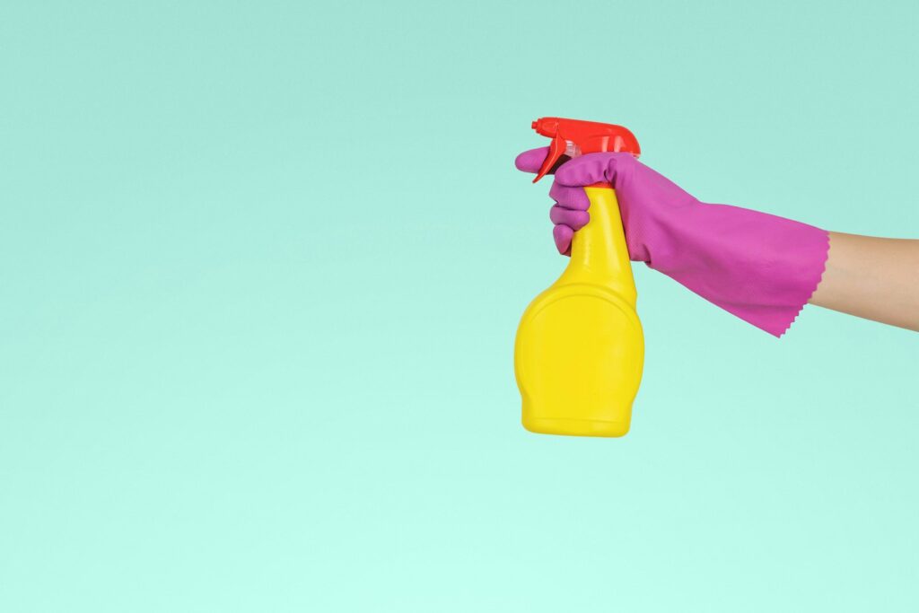 Flessen schoonmaakmiddel en bleekwater op een plank in de badkamer