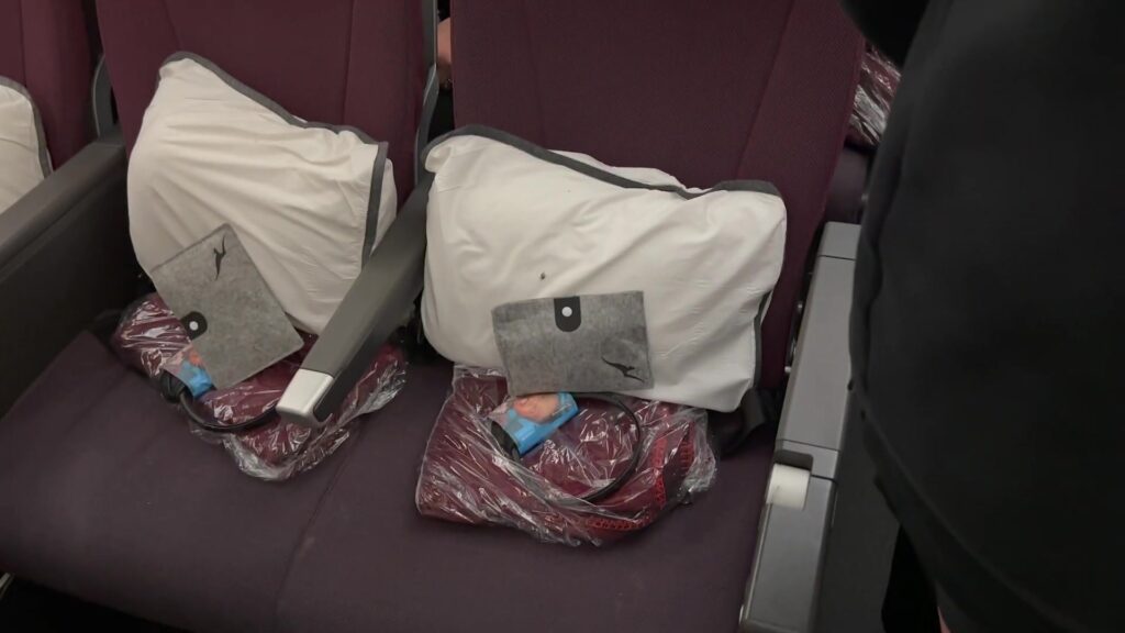 Stoelen in de economyclass van een vliegtuig met kussens en dekens