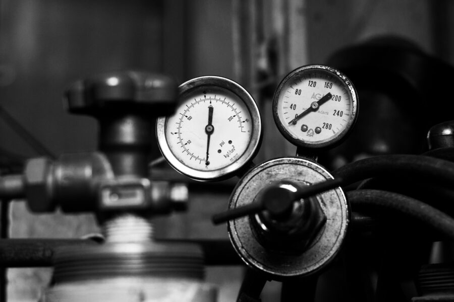 Cv-ketel aan de wand met drukmeter en leidingen eronder