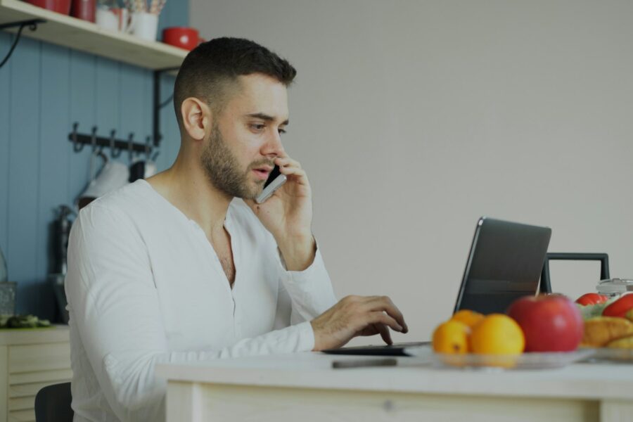 Iemand belt met een smartphone aan de keukentafel met een energierekening