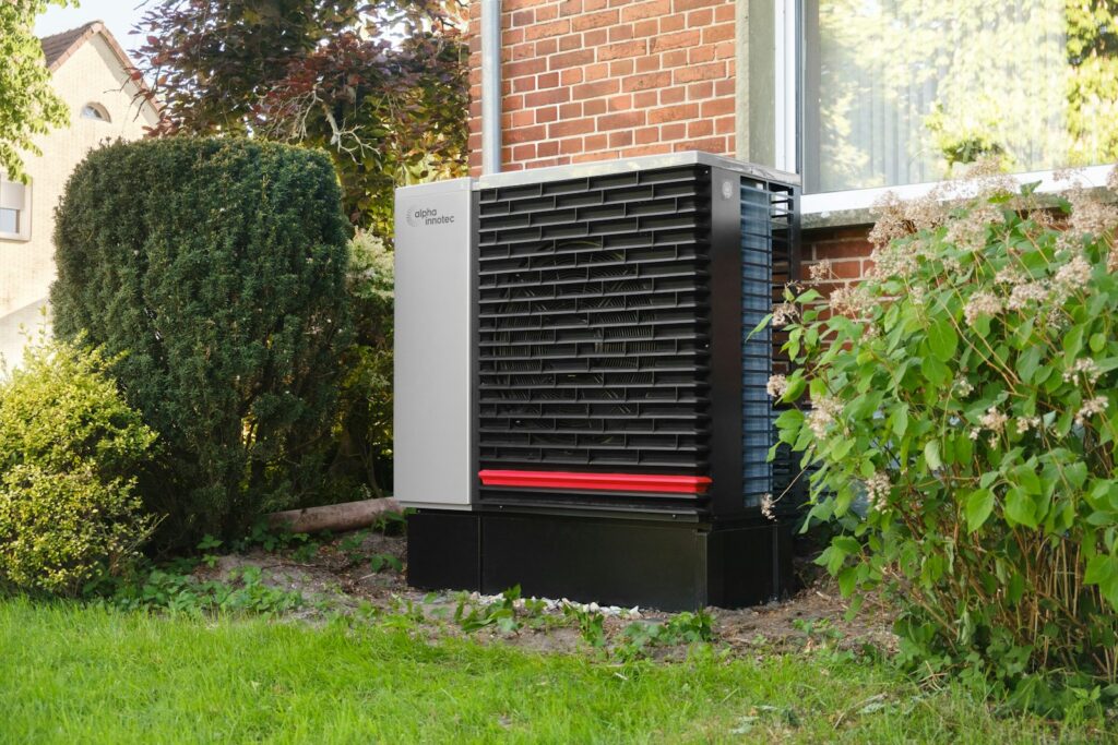 Buitenunit van een warmtepomp tegen de achtergevel van een woning