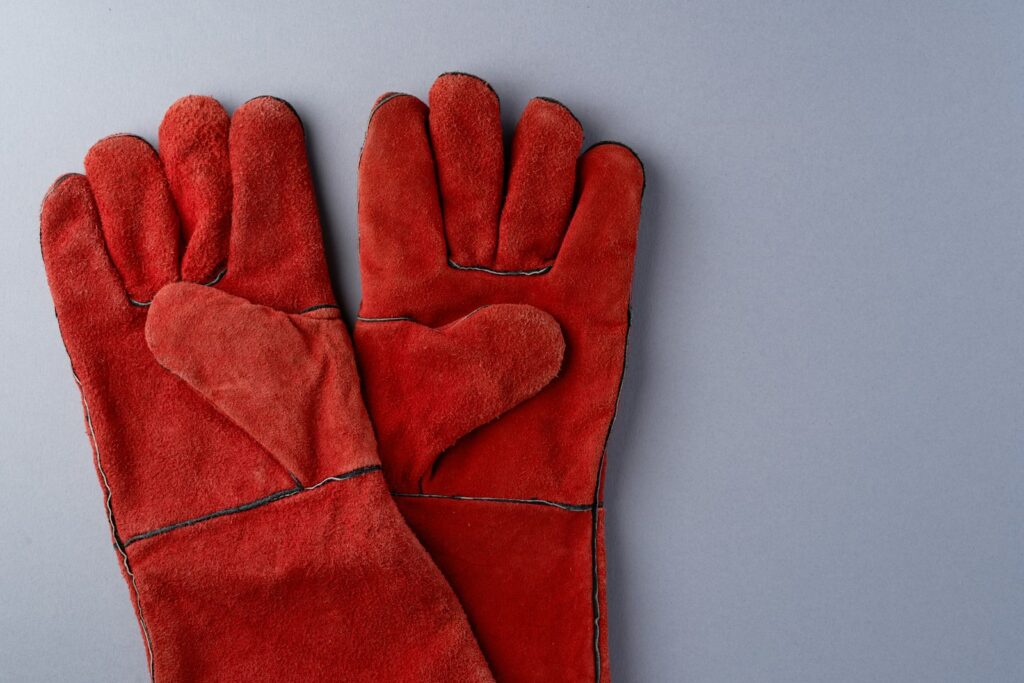 Handen in rubberen handschoenen die bladeren opruimen in een tuin