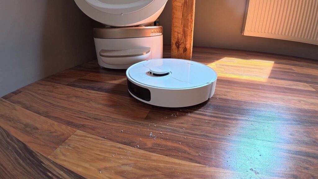 Witte robotstofzuiger met dweilfunctie op een houten vloer