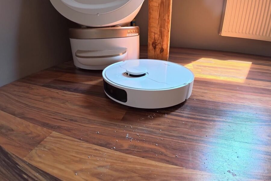 Witte robotstofzuiger met dweilfunctie op een houten vloer