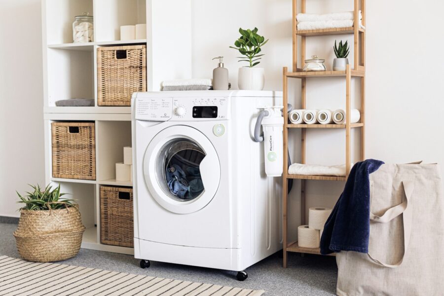 Wasdroger met open deur en een mand schone was ervoor